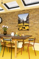 Modern dining area with exposed brick, yellow rubber floor, upcycled table and chairs