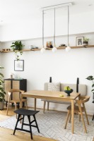 Scandinavian minimal contemporary dining room with wooden table, pendants, black and oak colour furniture, open shelves and bench seating