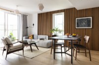 Open plan contemporary mid-century Japandi style living room with dining table and a slatted wall