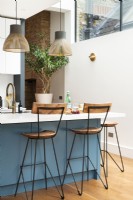 Contemporary modern kitchen in a side return extension with a blue island, wooden floors, light pendants, bar stools 