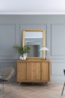 Modern wooden cabinet and gold framed mirror against grey wall