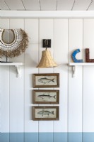 Framed paintings of fish on coastal cabin wall - detail 