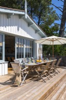 Outdoor dining area on raised decking next to coastal home in summer 