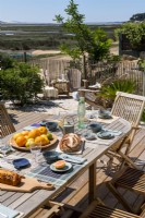 Outdoor dining table laid for lunch with coastal views in summer 