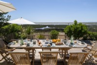 Outdoor dining table laid for lunch with coastal view in summer