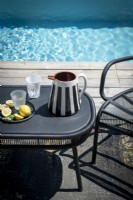 Water jug on black table next to swimming pool - detail