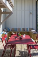 Red dining table and chairs on terrace with built-in bench seating