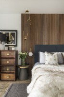 Classic style bedroom with fluffy throw over bed and slatted wall