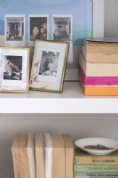 Detail of framed family photographs and books on shelves