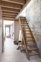 Wooden staircase in modern hallway with bare plaster wall