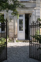Wrought iron gates open to front door of large country house 