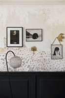 Display of paintings and photographs on bare plaster wall