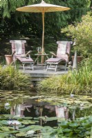 Recliners and parasol next to natural pond