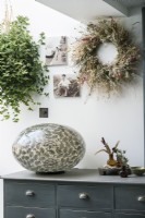 Floral wreath and large egg sculpture on sideboard