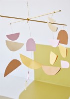 Detail of mobile made from cut out shapes of paper in muted tones