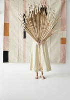 Woman hiding behind large dried palm leaf