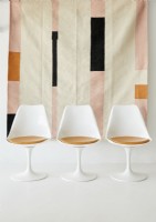 Tulip chairs next to wall hanging 