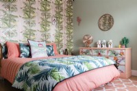 Modern bedroom with palm patterned wallpaper and bedspread and floral painted chest of drawers
