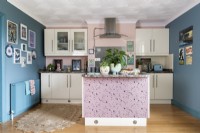 View into modern kitchen with white units and blue and pink walls