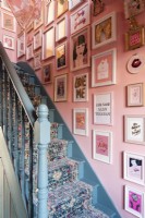 Blue painted staircase with stair runner, pink walls and salon style wall art display