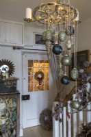 Christmas baubles hanging from ornate candelabra in hallway of country cottage
