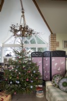 Christmas tree in living room with pink screen behind and apex roof