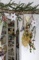 Decorative christmas foliage and baubles hanging in front of kitchen pantry