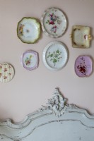 Collection of vintage plates hung above antique French bed