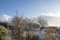 Snowy garden in Devon village, with summer house and shaped hedging