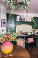 Kitchen with range and green painted cabinets and pink ceiling
