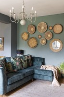 Green sofa in living space with salon style wall display of African baskets