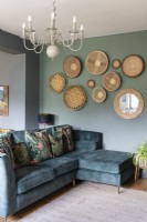 Green sofa in living space with salon style wall display of African baskets


