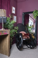 Black cane rocking chair in the corner of a colourful bedroom