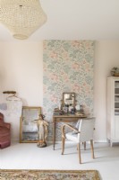 Dressing table against floral feature wall in country bedroom