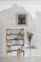 Bookshelves in alcove of white painted stone wall