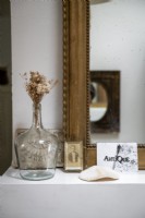 Detail of collectibles on shelf next to gilded mirror
