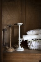 Basket of linen and old candlesticks on wooden unit - detail