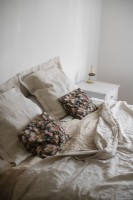 Floral cushions on unmade bed in country bedroom