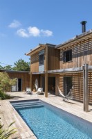Swimming pool outside modern wooden house in summer