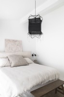 White bedroom with black lampshade on pendant light