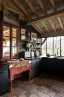 Black painted cupboards and red butchers block in country kitchen