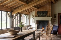 Rustic wooden table in country dining room with lit fireplace