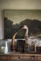 Taxidermy goose on wooden sideboard next to large painting