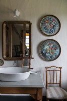 Detail of bathroom  sink and circular floral paintings on wall