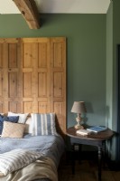 Wooden screen as headboard in country bedroom with green walls