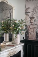 Flower arrangement on marble mantelpiece next to wallpapered wall