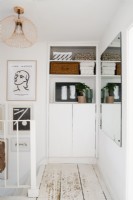 Bright white upstairs hallway with built-in storage and cupboards. Framed pictures hang on the walls. 