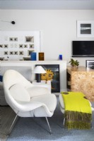 Modern white armchair and ottoman with yellow throw.