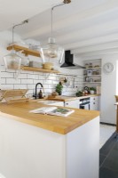 Contemporary L-shaped Kitchen with white subway tiles and wooden work surface. Under the window is a L-shaped banquette seating area