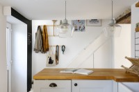 In the foreground is a contemporary L-shaped Kitchen with white subway tiles and wooden work surface and grey cabinets. 